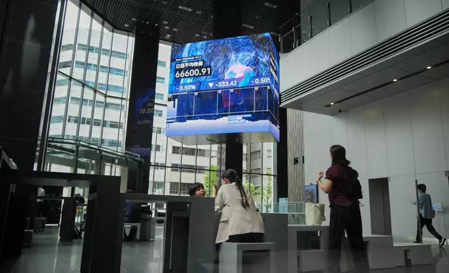 People gather in front of an electronic stock board showing Japan's Nikkei index at a securities firm Tuesday, June 2, 2026, in Tokyo. (AP Photo/Eugene Hoshiko)