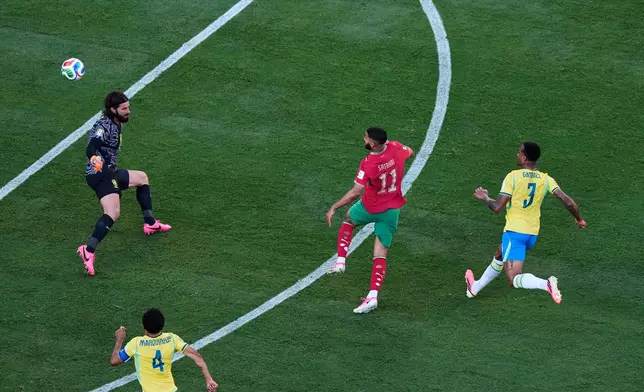 Morocco's Ismael Saibari (11) scores over Brazil goalkeeper Alisson Becker, left, as Brazil's Gabriel Magalhaes (3) and Marquinhos (4) watch during the World Cup Group C soccer match in East Rutherford, N.J., near New York, Saturday, June 13, 2026. (AP Photo/Matt Slocum)