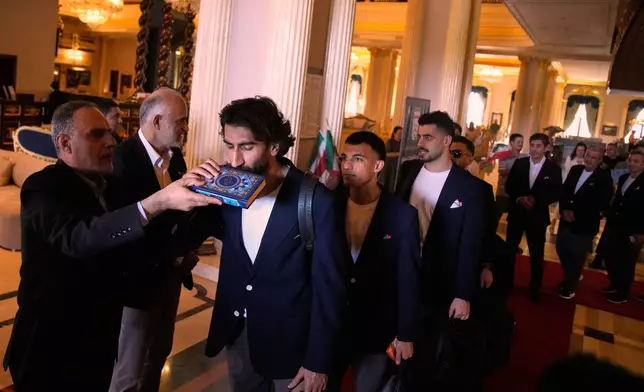 Iran's players kiss the Muslim's holiest book Quran as they leave to Antalya airport, southern Turkey, Saturday, June 6, 2026, before departing to Tijuana, Mexico, for the World Cup soccer tournament. (AP Photo/Khalil Hamra)