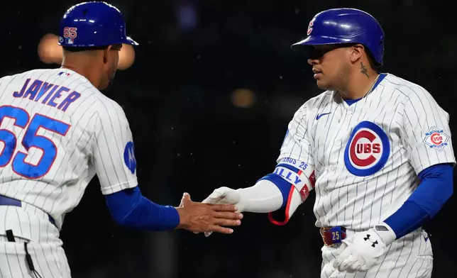Chicago Cubs' Moisés Ballesteros, right, celebrates with first base coach Jose Javier after hitting a one-run single during the third inning of a baseball game against the San Francisco Giants in Chicago, Sunday, June 7, 2026. (AP Photo/Nam Y. Huh)