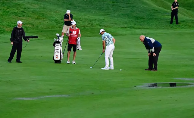 Viktor Hovland, center, of Norway, moves his ball due to standing water without penalty on the 18th fairway during the final round of the Travelers Championship golf tournament at TPC River Highlands, Sunday, June 28, 2026, in Cromwell, Conn. (AP Photo/Jessica Hill)
