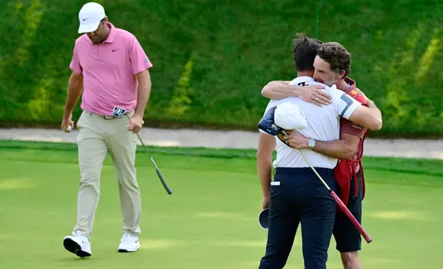 Viktor Hovland, of Norway, right, hugs his caddie Shay Knight as Scottie Scheffler, left, walks off the green on the first playoff hole of the Travelers Championship golf tournament at TPC River Highlands, Monday, June 29, 2026, in Cromwell, Conn. (AP Photo/Jessica Hill)r
