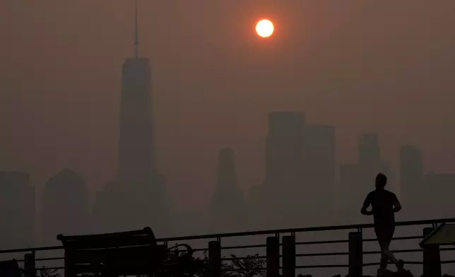 FILE - A man runs in front of the sun rising over the lower Manhattan skyline in Jersey City, N.J., June 8, 2023. (AP Photo/Seth Wenig, File)