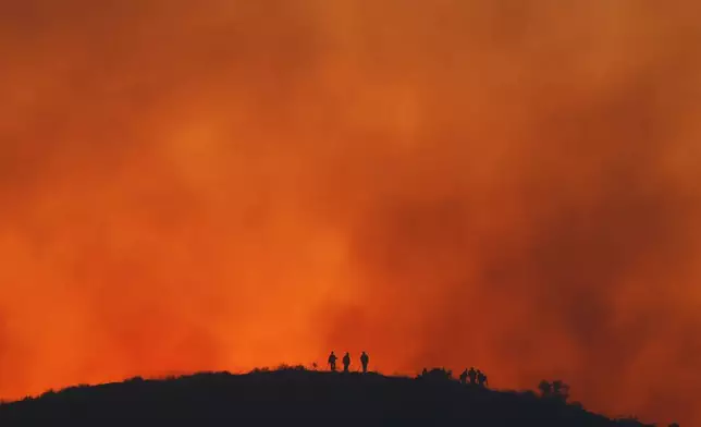 FILE - Firefighters are silhouetted amid an operation to control the Sandy Fire, May 19, 2026, in Simi Valley, Calif. (AP Photo/Caroline Brehman, File)