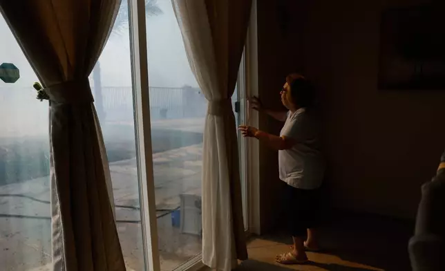 FILE - Mayra Long looks from inside her home as the Sandy Fire approaches May 19, 2026, in Simi Valley, Calif. (AP Photo/Caroline Brehman, File)