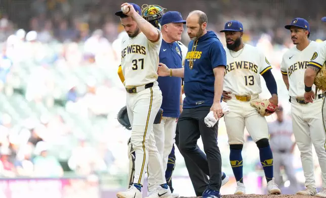Milwaukee Brewers pitcher DL Hall (37) walks off the mound with Milwaukee Brewers' Head Athletic Trainer Brad Epstein during the fifth inning of a baseball game against the San Francisco Giants Thursday, June 4, 2026, in Milwaukee. (AP Photo/Kayla Wolf)