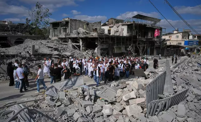 Lebanese Shiite men pass buildings destroyed by Israeli strikes during an Ashoura procession, when Shiites commemorate the martyrdom of Imam Hussein, the grandson of the Prophet Muhammad, in Nabatiyeh, southern Lebanon, Friday, June 26, 2026. (AP Photo/Hassan Ammar)