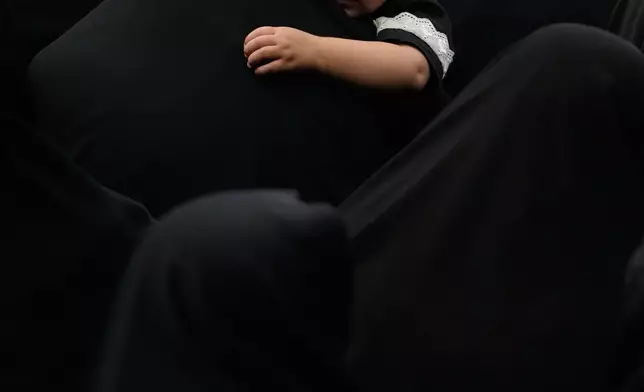 A woman holds a child during a mourning ceremony in Tehran, Iran, Thursday, June 25, 2026, in the holy day of Ashoura which commemorates the martyrdom of Imam Hussein, a grandson of the Prophet Muhammad, and his family and companions at the Battle of Karbala in A.D. 680, in present-day Iraq, after refusing to pledge allegiance to the Umayyad caliphate. (AP Photo/Vahid Salemi)