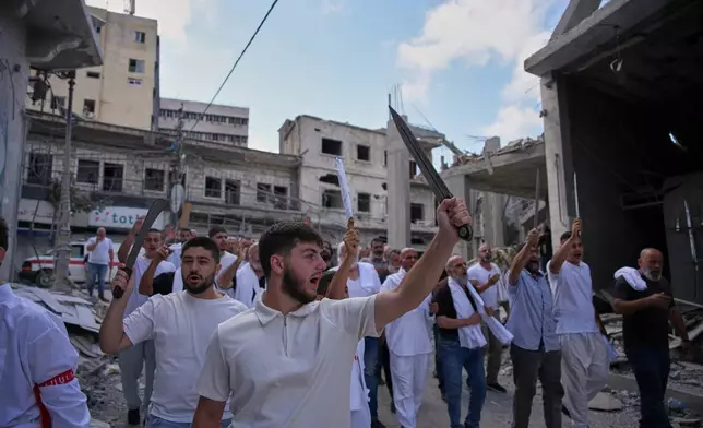 Lebanese Shiite men raise swords during an Ashoura procession, when Shiites commemorate the martyrdom of Imam Hussein, the grandson of the Prophet Muhammad, in Nabatiyeh, southern Lebanon, Friday, June 26, 2026. (AP Photo/Hassan Ammar)
