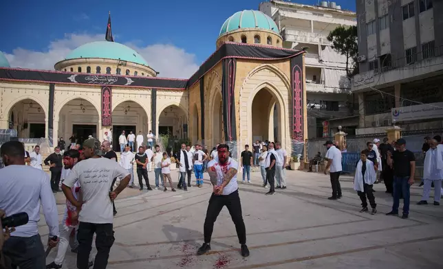 A Lebanese Shiite strikes his head with a sword, bleeding from self-inflicted wounds, during Ashoura, when Shiites commemorate the martyrdom of Imam Hussein, the grandson of the Prophet Muhammad, in In Nabatiyeh, southern Lebanon, Friday, June 26, 2026. (AP Photo/Hassan Ammar)