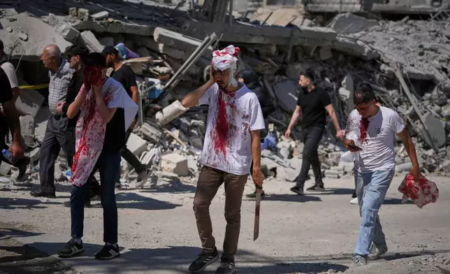 EDS NOTE: GRAPHIC CONTENT - Bleeding from self-inflicted ceremonial head wounds, Lebanese Shiite men walk past buildings destroyed by Israeli strikes during Ashoura, when Shiites commemorate the martyrdom of Imam Hussein, the grandson of the Prophet Muhammad, in Nabatiyeh, southern Lebanon, Friday, June 26, 2026. (AP Photo/Hassan Ammar)