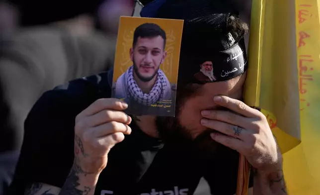 A man holds a portrait of his killed brother who was a Hezbollah fighter, as he mourns while listening to the death story of Imam Hussein during the holy day of Ashoura that commemorates the 7th century martyrdom of the Prophet Muhammad's grandson Hussein, in Dahiyeh, Beirut's southern suburbs, Lebanon, Friday, June 26, 2026. (AP Photo/Hussein Malla)