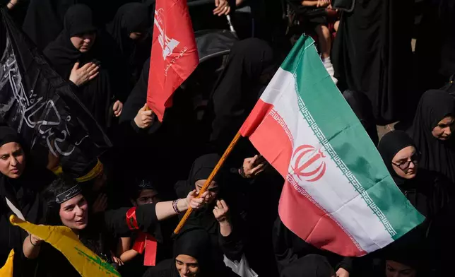 A Hezbollah supporter waves an Iranian flag, as she marches during the holy day of Ashoura that commemorates the 7th century martyrdom of the Prophet Muhammad's grandson Hussein, in Dahiyeh, Beirut's southern suburbs, Lebanon, Friday, June 26, 2026. (AP Photo/Hussein Malla)