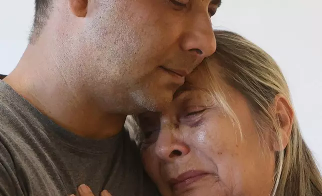 Grian Serrano embraces his mother Ingrid Rochabrun at the home where they are staying with relatives in Caracas, Venezuela, after surviving the back-to-back earthquakes that destroyed their apartment building in Caraballeda, Monday, June 29, 2026. Serrano also survived the 1999 mudslides that struck La Guaira. (AP Photo/Pedro Mattey)