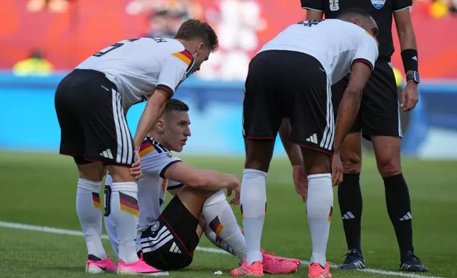 Germany's Nico Schlotterbeck, centre, waits to receive treatment following an injury during the World Cup Group E soccer match between Germany and Ivory Coast in Toronto, Saturday, June 20, 2026. (AP Photo/Stephanie Scarbrough)