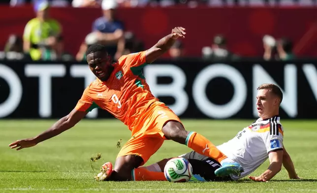 Ivory Coast's Ange-Yoan Bonny (9) is tackled by Germany's Nico Schlotterbeck (15) during the World Cup Group E soccer match between Germany and Ivory Coast in Toronto, Saturday, June 20, 2026. (Nathan Dennette/The Canadian Press via AP)