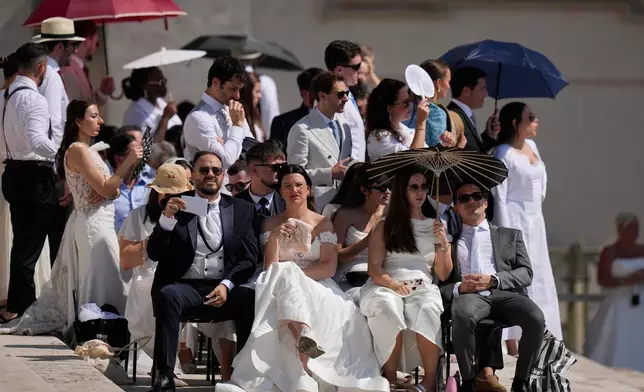 Faithful shelter for the hot sun as they wait for Pope Leo's XIV weekly general audience in St. Peter's Square at The Vatican, Wednesday, June 24, 2026. (AP Photo/Alessandra Tarantino)