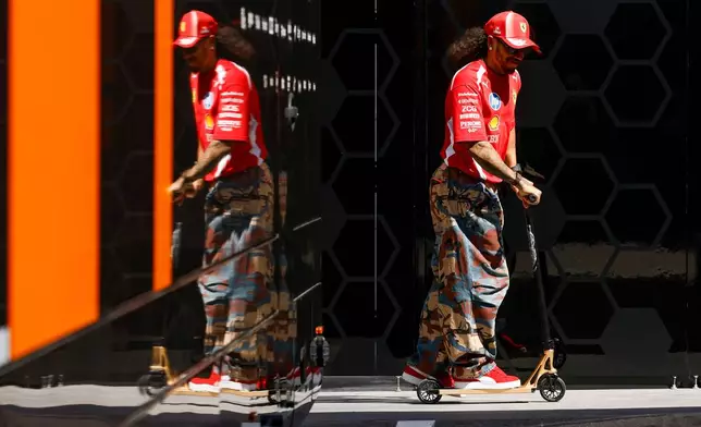 Ferrari driver Lewis Hamilton of Britain, rides a scooter at the Barcelona Catalunya racetrack in Montmelo, near Barcelona, Spain, Thursday, June 11, 2026. (AP Photo/ Joan Monfort)