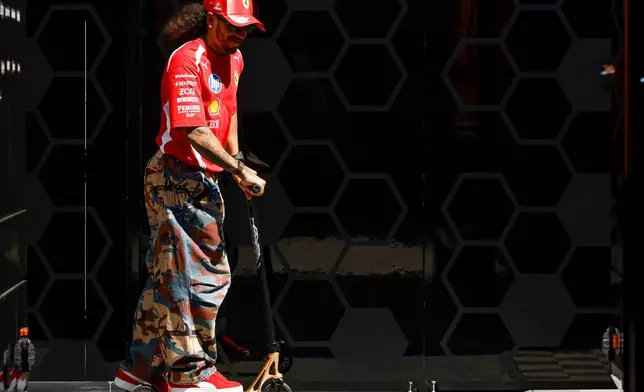 Ferrari driver Lewis Hamilton of Britain rides a scooter at the Barcelona Catalunya racetrack in Montmelo, near Barcelona, Spain, Thursday, June 11, 2026. (AP Photo/ Joan Monfort)