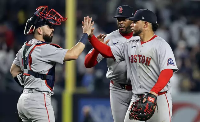 Boston Red Sox first baseman Willson Contreras, front right, high-fives catcher Connor Wong, left, in front of pitcher Aroldis Chapman, back right, after defeating the New York Yankees in a baseball game Friday, June 5, 2026, in New York. (AP Photo/Adam Hunger)