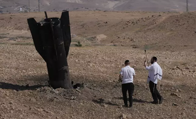 People inspect the wreckage of an Iranian missile that landed near the West Bank city of Jericho Monday, June 8, 2026. (AP Photo/Mahmoud Illean)