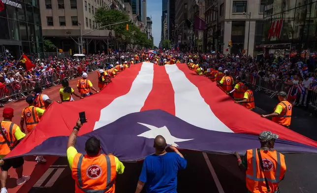 A giant Puerto Rican flag is carried during the National Puerto Rican Day Parade, Sunday, June 14, 2026 in New York. (AP Photo/Adam Gray)