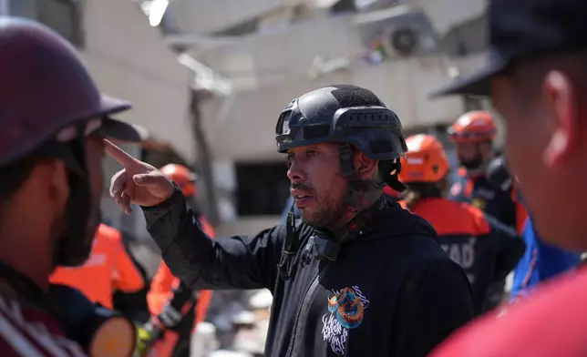 Volunteer Jean Sosa, who joined rescue teams searching for earthquake survivors, explains what he saw after going under the rubble of a building where rescuers are trying to reach trapped people in La Guaira, Venezuela, Monday, June 29, 2026. (AP Photo/Matias Delacroix)