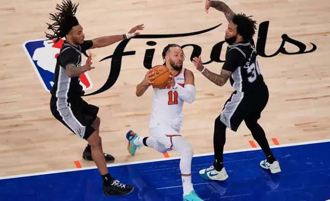 New York Knicks guard Jalen Brunson (11) drives past San Antonio Spurs defenders during the second half of Game 3 of the NBA Finals basketball series, Monday, June 8, 2026, in New York. (AP Photo/Yuki Iwamura)