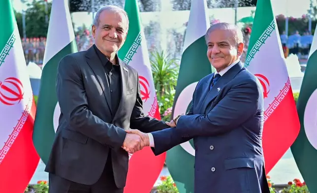 In this photo released by Pakistan Prime Minister Office, Iran's President Masoud Pezeshkian, left, shakes hands with Pakistan's Prime Minister Shehbaz Sharif during a welcome ceremony in Islamabad, Pakistan, on Tuesday, June 23, 2026. (Pakistan Prime Minister Office via AP)