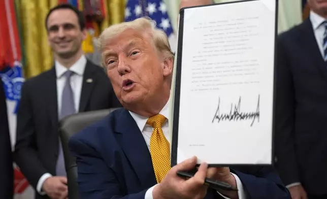 President Donald Trump holds up a signed executive order about quantum computing, in the Oval Office of the White House, Monday, June 22, 2026, in Washington. (AP Photo/Jacquelyn Martin)