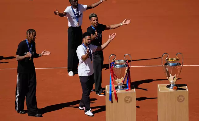 Paris Saint-Germain players Bradley Barcola, left, Warren Zaire-Emery, center, Desire Doue, right, and Ousmane Dembele, rear, present two Champions League trophies at the French Open in Paris, Monday, June 1, 2026. (AP Photo/Christophe Ena)