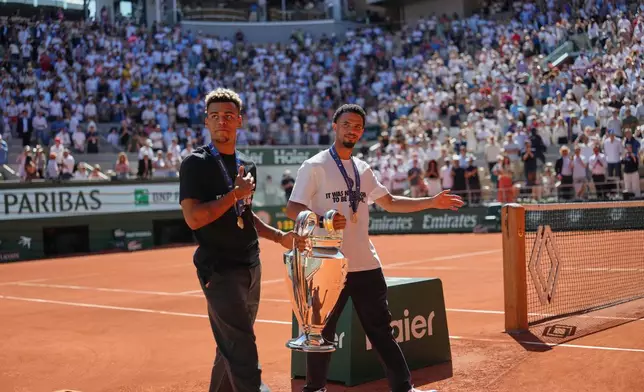 PSG's Desire Doue, left, and Warren Zaire-Emery walk onto the center court with Chgampions league trophy at the French Open tennis tournament in Paris, Monday, June 1, 2026. (AP Photo/Aurelien Morissard)