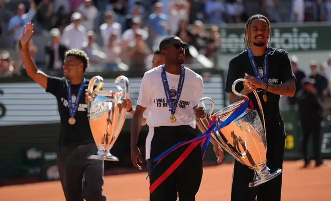 PSG's Ousmane Dembele, left, and Bradley Barcola walk onto the court with the Champions League trophy during the French Open in Paris, Monday, June 1, 2026. (AP Photo/Aurelien Morissard)