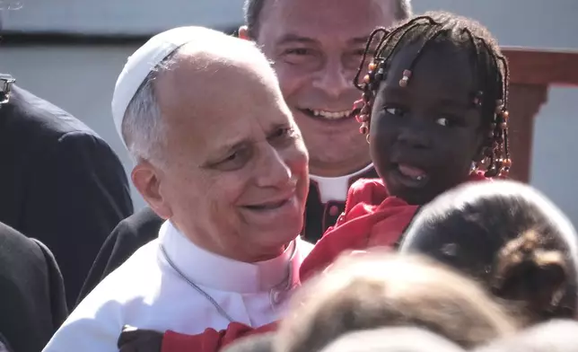 Pope Leo XIV holds a young assistant as he arrives for a meeting with migrants at the Las Raíces reception center in San Cristóbal de La Laguna, Tenerife, Spain, Friday, June 12, 2026. (AP Photo/Arturo Rodriguez)