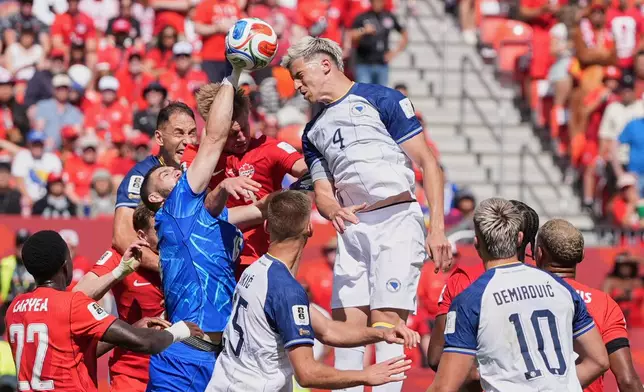Canada goalkeeper Maxime Crepeau punches the ball clear as Bosnia's Tarik Muharemovic attempts to head the ball during the World Cup Group B soccer match between Canada and Bosnia in Toronto, Friday, June 12, 2026. (AP Photo/Stephanie Scarbrough)