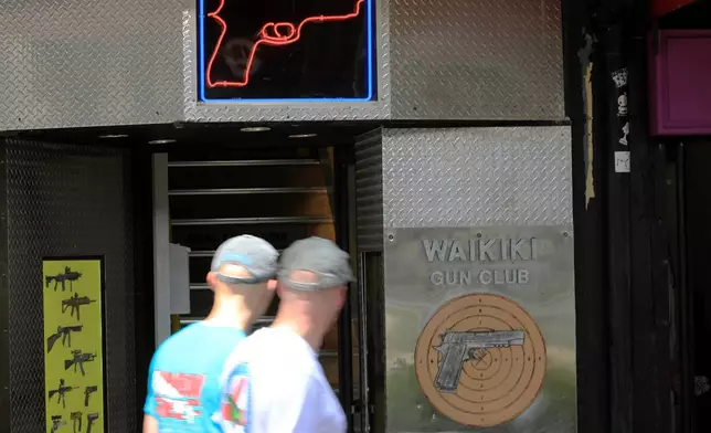 FILE - People walk past a gun club in Honolulu, June, 23, 2022. (AP Photo/Marco Garcia, File)