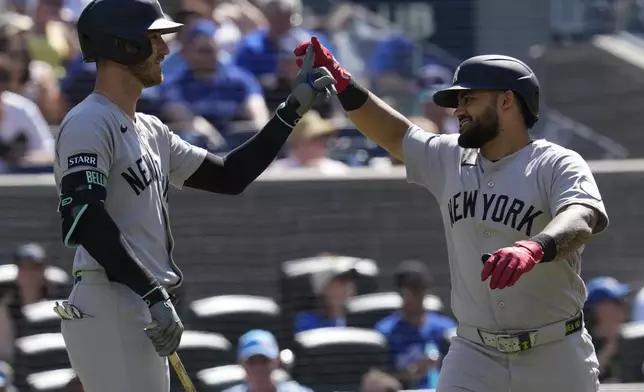 New York Yankees' Jasson Dominguez, right, is congratulated by Cody Bellinger (35) after hitting a solo home run against the Toronto Blue Jays during the fourth inning of a baseball in Toronto, Saturday, June 13, 2026. (Frank Gunn/The Canadian Press via AP)