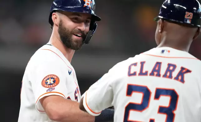 Houston Astros' Collin Price, left, greets first base coach Dave Clark (23) after being walked in his rookie debut by Pittsburgh Pirates starting pitcher Jared Jones during the second inning of a baseball game, Thursday, June 4, 2026, in Houston. (AP Photo/Karen Warren)