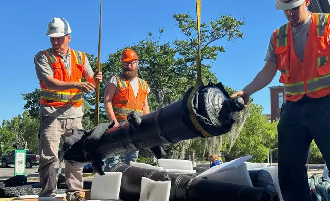 Terry Koller, Bradford Shields and Joseph Robinson steady a cannon, which sunk to the bottom of the Savannah River during the American Revolution, as it's hoisted from the bed of a truck at the Savannah History Museum in Savannah, Ga., on Wednesday, June 3, 2026. (AP Photo/Russ Bynum)