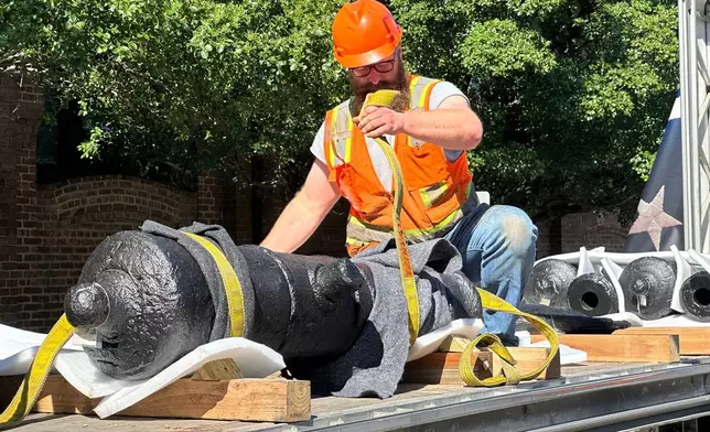 Bradford Shields fastens lifting straps to a cannon, which sunk to the bottom of the Savannah River during the American Revolution, on a flatbed truck at the Savannah History Museum in Savannah, Ga., on Wednesday, June 3, 2026. (AP Photo/Russ Bynum)
