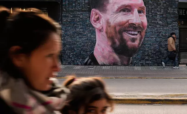 People walk past a mural of Lionel Messi by artist Leonel Garcia, which includes the names of local residents inscribed by them as a tribute to the soccer star, in Berazategui, on the outskirts of Buenos Aires, Argentina, Monday, June 22, 2026. (AP Photo/Gustavo Garello)