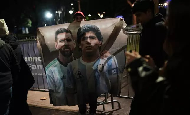 A fan holds a poster of soccer stars Lionel Messi and Diego Maradona after watching the World Cup soccer match between Argentina and Algeria in Buenos Aires, Argentina, Tuesday, June 16, 2026. (AP Photo/Rodrigo Abd)
