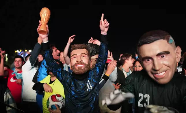 Fans with masks of Argentina's Lionel Messi, center, and Emiliano Martinez gather to watch the World Cup soccer match between Argentina and Algeria in Buenos Aires, Argentina, Tuesday, June 16, 2026. (AP Photo/Rodrigo Abd)