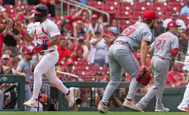 St. Louis Cardinals' Jose Fermin, left, celebrates as he runs in to score on a throwing error by Cincinnati Reds pitcher Sam Moll (50) during the eighth inning of a baseball game Sunday, June 7, 2026, in St. Louis. (AP Photo/Jeff Roberson)
