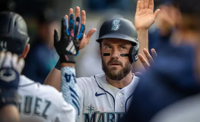 Seattle Mariners' Patrick Wisdom is congratulated by teammates in the dugout after scoring a run during the fourth inning of a baseball game against the New York Mets, Tuesday, June 2, 2026, in Seattle. (AP Photo/Stephen Brashear)