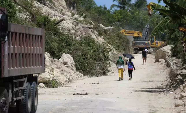People walk past a landslide following an earthquake in Sarangani province, Philippines, Wednesday, June 10, 2026. (AP Photo/Basilio Sepe)
