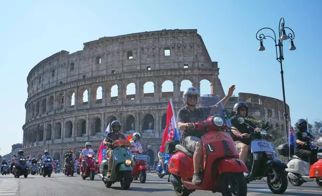 Vespa enthusiasts parade in front of the Colosseum during celebrations for the 80th anniversary of the Vespa scooter, in Rome, Saturday, June 27, 2026. (AP Photo/Alessandra Tarantino)