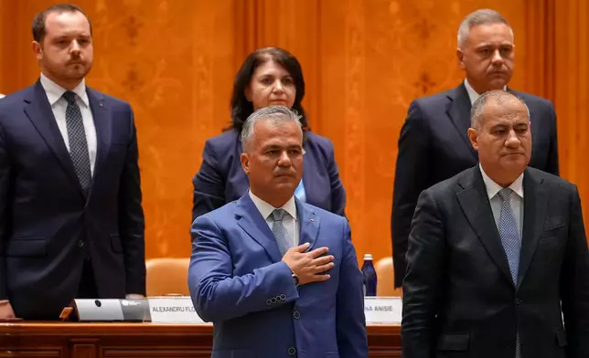Romanian Prime Minister designate Adrian Vestea, centre, listens to the national anthem during a joint parliament session called to give a vote of confidence for the new government team in Bucharest, Romania, Monday, June 22, 2026. (AP Photo/Vadim Ghirda)