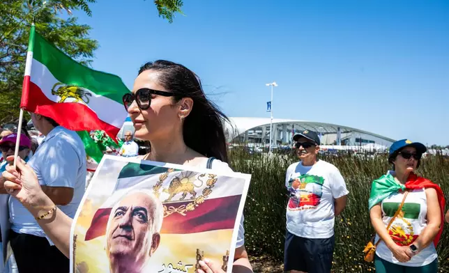 A woman holds a flag and poster during a protest in reaction to FIFA's ban of Iran's pre-revolutionary flag inside World Cup stadiums Sunday, June 7, 2026, in Inglewood, Calif. (AP Photo/Benjamin Hanson)