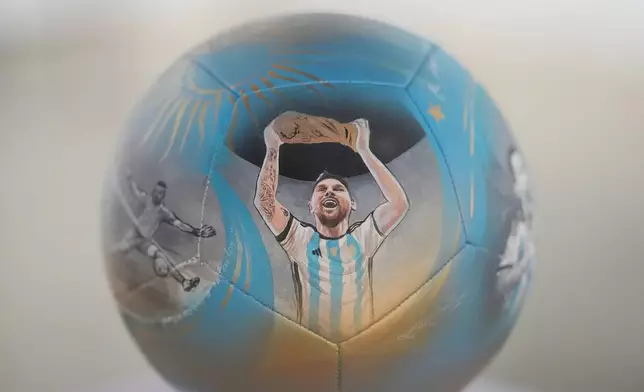 Lionel Messi lifting a trophy is depicted on a soccer ball hand-painted by artist Lili Cantero to commemorate Argentina's 2022 World Cup victory in Qatar, part of a neighborhood-wide soccer ball art trail and World Cup-themed treasure hunt planned for Miami's Wynwood district, Thursday, June 4, 2026. (AP Photo/Rebecca Blackwell)